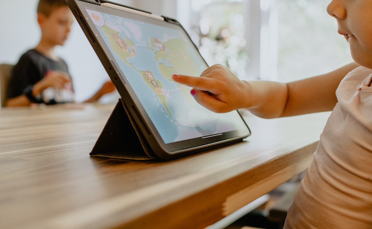 Child's hand using a tablet with a colorful game.